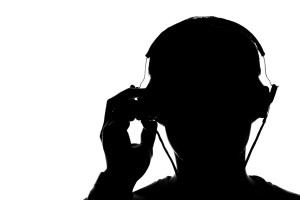 Silhouette eines jungen Mannes, der mit Kopfhörern Musik hört — Stockfoto