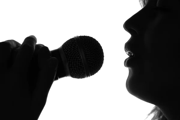 Silueta de una mujer cantando con un micrófono en las manos —  Fotos de Stock