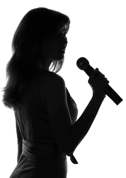 Sylwetka kobiety śpiewają z mikrofonu w ręce — Zdjęcie stockowe