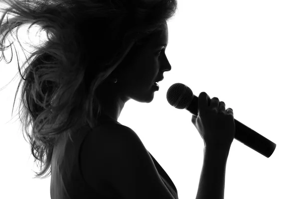 Silhouette di una donna che canta con un microfono in mano — Foto Stock
