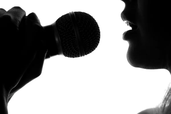 Silueta ženy zpívají s mikrofonem v ruce — Stock fotografie