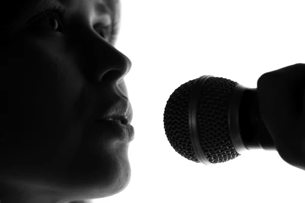 Silhueta de uma mulher cantando com um microfone nas mãos — Fotografia de Stock