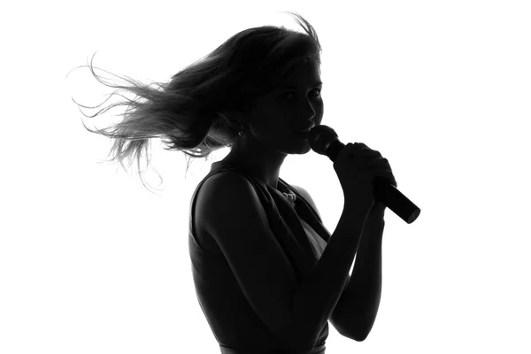 Bir kadının bir mikrofonla şarkı silüeti — Stok fotoğraf