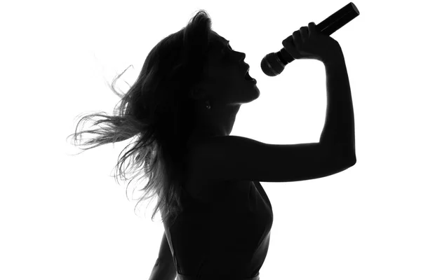 Silueta de una mujer cantando con un micrófono en las manos — Foto de Stock