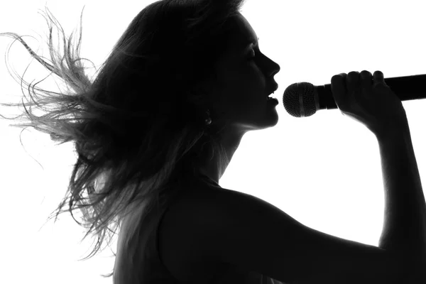 Silhouette di una donna che canta con un microfono — Foto Stock