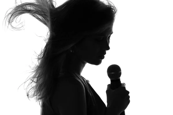 Sziluettjét egy nőt énekelni egy mikrofonnal a kezében — Stock Fotó
