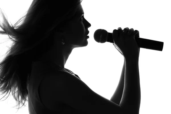 Silhouette di una donna che canta con un microfono — Foto Stock