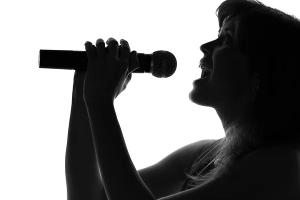 Silhueta de uma mulher cantando com um microfone nas mãos — Fotografia de Stock