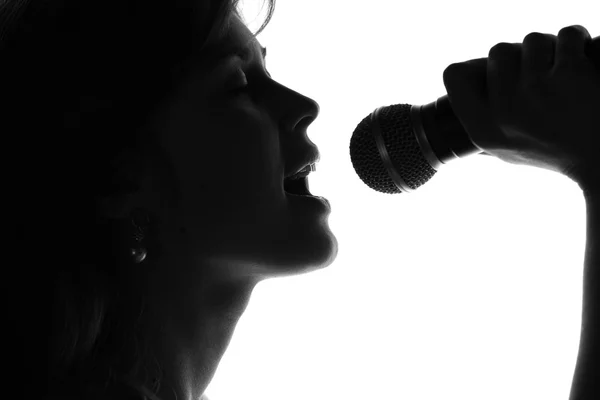 Silhouette di una donna che canta con un microfono in mano — Foto Stock