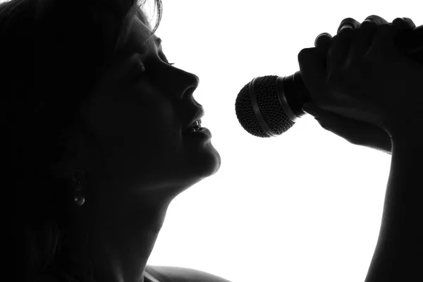 Silhouette di una donna che canta con un microfono in mano — Foto Stock
