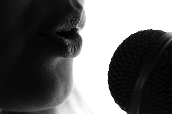 Silhueta de uma mulher cantando com um microfone nas mãos — Fotografia de Stock