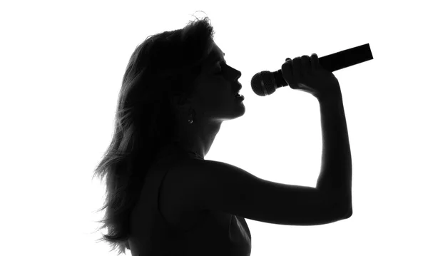 Σιλουέτα μιας γυναίκας που τραγουδούν με το μικρόφωνο στα χέρια — Φωτογραφία Αρχείου