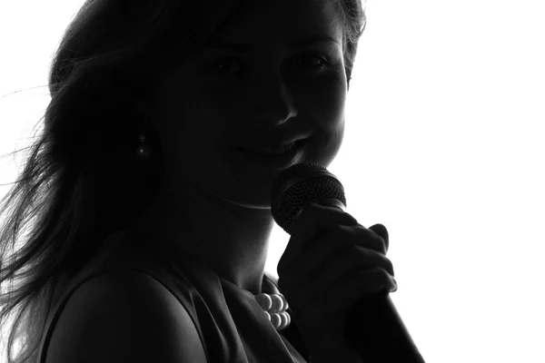 Silhouette di una donna che canta con un microfono in mano — Foto Stock