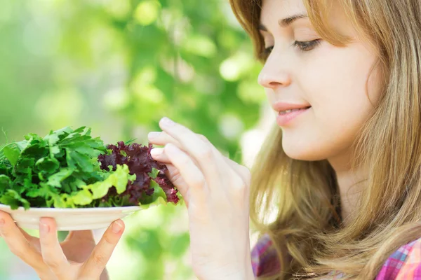 Woman holding a plate with fresh greens — Stock Photo, Image