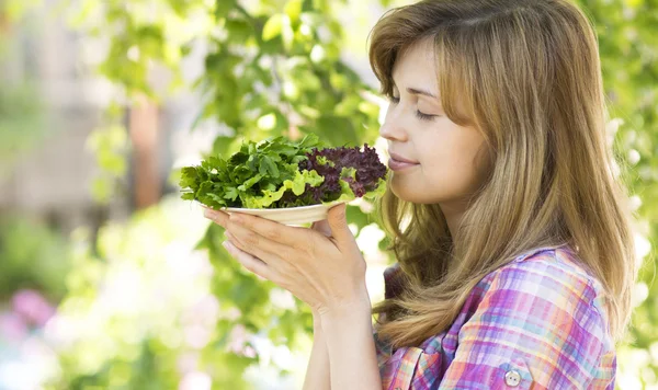 Young woman enjoying the smell of greenery laid nicely on a plat — Stockfoto