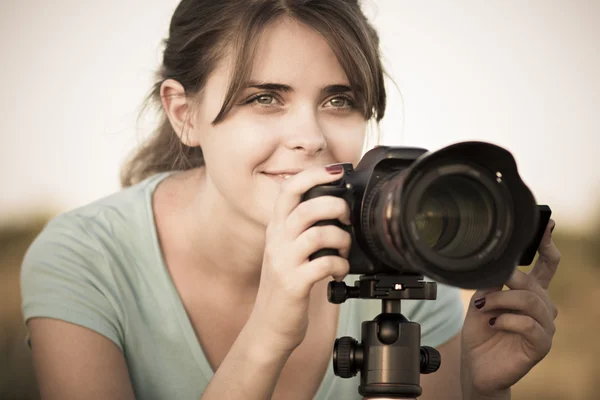 Винтажное фото красивой женщины, работающей с фотоаппаратом на стойке в поле — стоковое фото