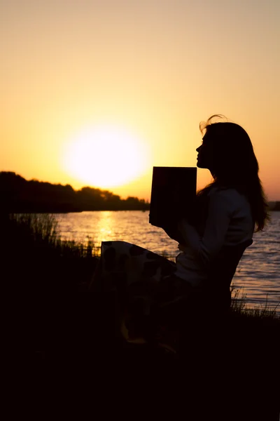 Silhouette di una bella giovane donna riflettere sulle informazioni lette in un libro sulla natura — Foto Stock