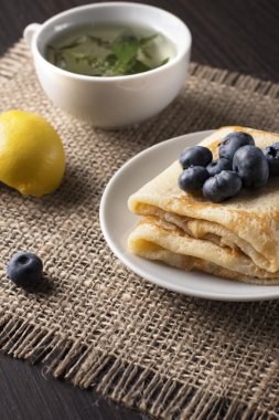 mutfak masasında lezzetli kokulu Kahvaltı: bir fincan sıcak çay, kızarmış krep, yaban mersini, yıldız anason, limon