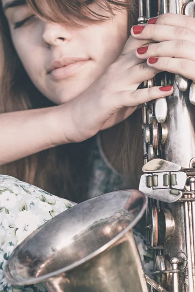 緑の草を背景に手にサックスを持つ若い女性の夏の肖像画 — ストック写真