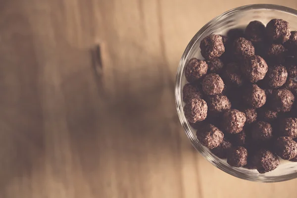 Cow's milk in a glass on the kitchen table and chocolate corn flakes — Stock Photo, Image