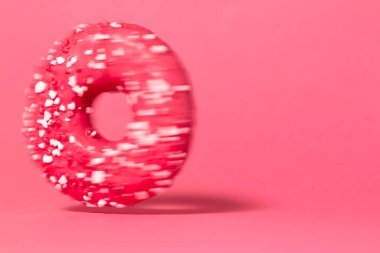 Hızlı hareket eden donut renkli pembe stüdyo arka planında izole edilmiş. Delikli yuvarlak pasta, konsept tatil eğlencesi, lezzetli yemekler.