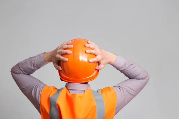 back of contruction worker clutching his head in helmet on grey studio background looking, foreman shocked