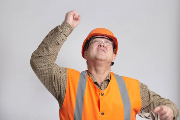 fat middle-aged building contractor in hard hat waved his hand looking up on white isolated background, foreman controls work