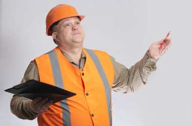 Belgeleri gri arka planda, inşaat sürecinin kontrolünde olan sert şapkalı orta yaşlı, şişman mühendis.