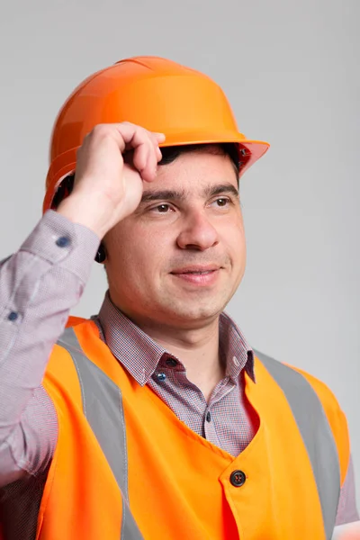 灰色のスタジオの背景挨拶のハード帽子で成功した若い建設労働者の肖像画 制服のエンジニア — ストック写真