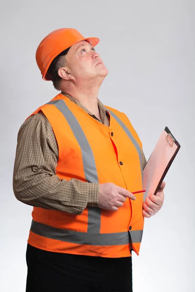 中年の脂肪エンジニアでハード帽子とドキュメントで腕の下に灰色の背景を検索して管理する — ストック写真