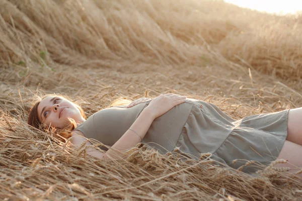 白种人怀孕的年轻红头发女子 夏天黄昏时分躺在麦田里 未来的母亲在大自然中放松 健康快乐的怀孕观念 新的生命 — 图库照片