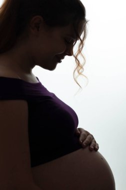 Güzel, mutlu, hamile bir kadının portresi. Elleri karnında, müstakbel anne bakımı ve beyaz izole bir arka planda sevişme. Gelecekteki yaşam konsepti.