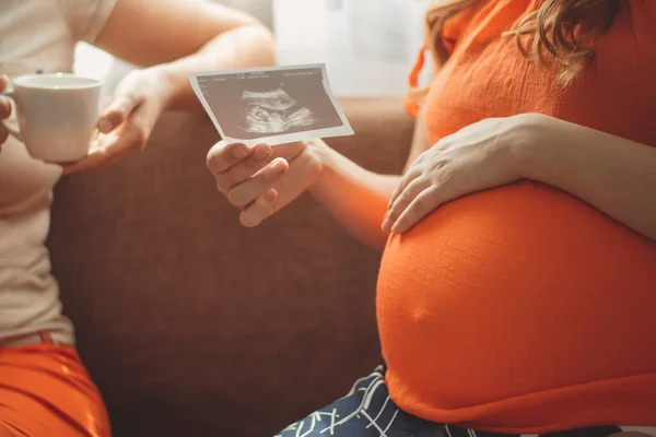 与女友坐在厨房里谈论超声波快照 母性观念 怀孕和友谊的年轻孕妇 — 图库照片