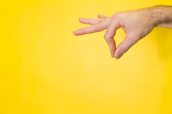 Mano masculina sosteniendo su producto sobre fondo amarillo — Foto de Stock