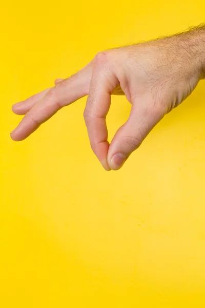 Mano maschile tenendo il prodotto su sfondo giallo — Foto Stock