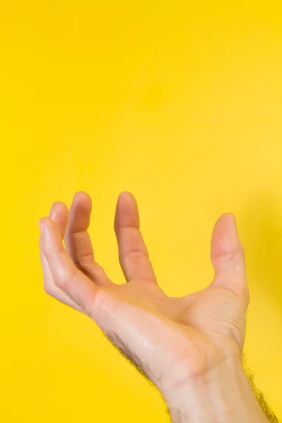 Αρσενική χέρι που κρατά το προϊόν σας σε κίτρινο φόντο — Φωτογραφία Αρχείου