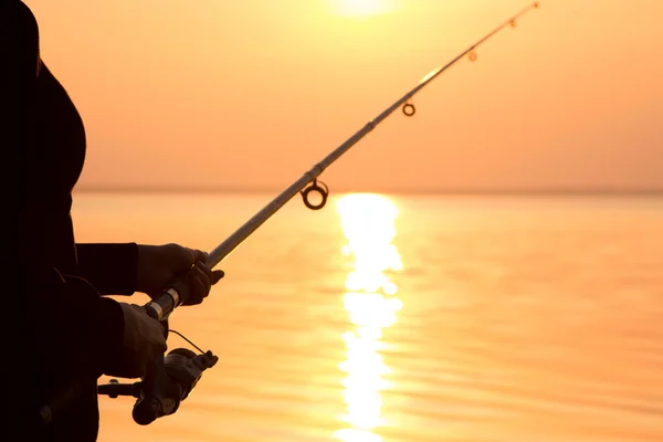 Junges Mädchen angelt bei Sonnenuntergang am Meer — Stockfoto