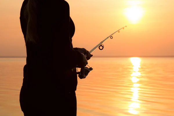 Silhouette di una ragazza sulla riva del fiume con una canna da pesca — Foto Stock