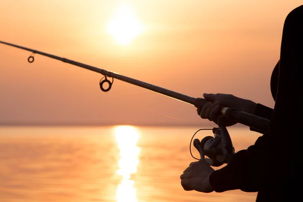 Giovane ragazza pesca al tramonto vicino al mare — Foto Stock