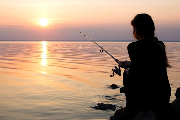 年轻的姑娘在海边日落钓鱼 — 图库照片