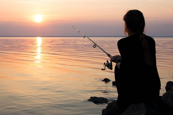 Fiatal lány, horgászat, napnyugtakor a tenger közelében — Stock Fotó