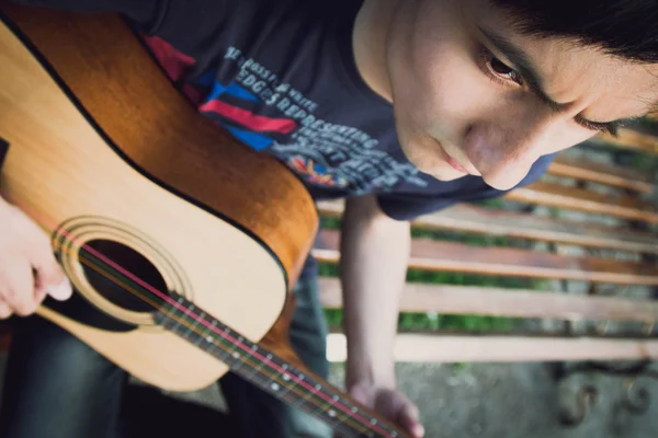 Молодий хлопець грає на гітарі в парку — стокове фото