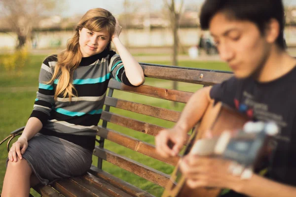 Young guy playing guitar girl in the park — Stock Photo, Image