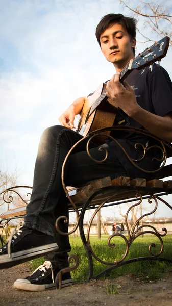 Junger Mann spielt Gitarre im Park — Stockfoto