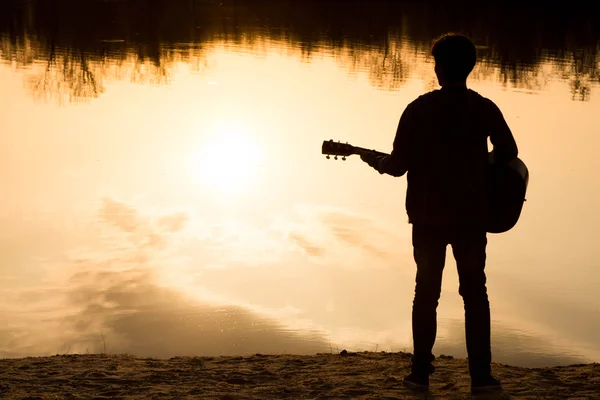 Силуэт молодого человека на пляже с гитарой — стоковое фото