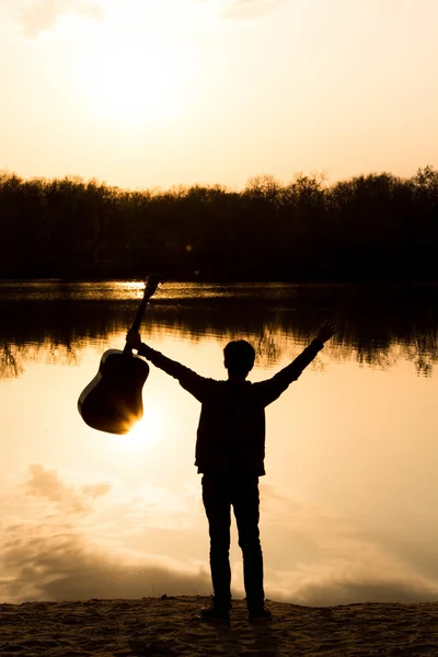 Silhouette of a young man on the beach with a guitar — Stock Photo, Image