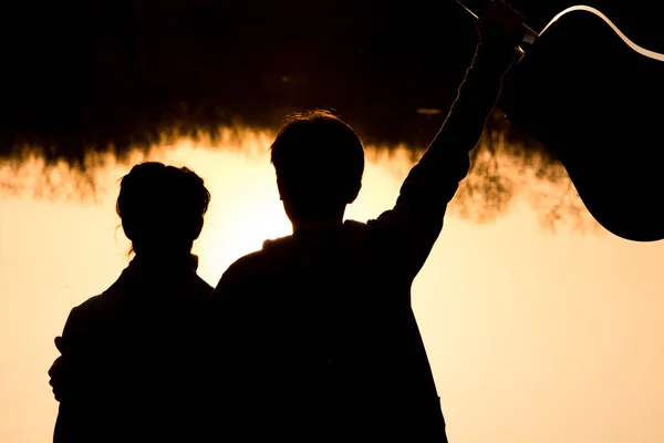 Silhouette eines Jungen und eines Mädchens am Strand mit einer Gitarre — Stockfoto