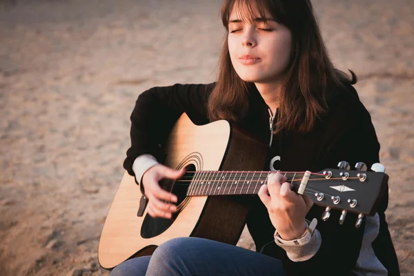Young girl playing guitar sitting on the sand — Stock Photo, Image