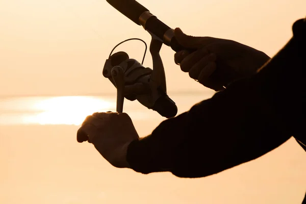 Silueta de pescador al atardecer cerca del mar con caña de pescar — Foto de Stock