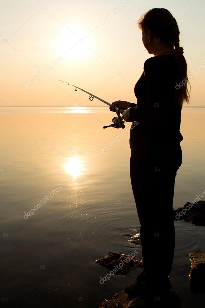 Silhouette of a young girl fishing at sunset near the sea — Stock Photo ©  fantom_rd #70696575